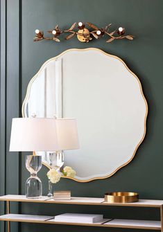 a mirror on the wall above a table with a lamp and vase in front of it