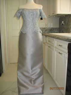 a dress on display in a kitchen with marble counter tops and white cabinets behind it