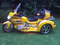 a yellow motorcycle parked on top of a lush green field