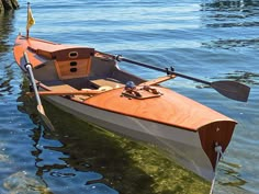 an orange and white boat in the water with oars on it's side