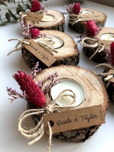 small candles are wrapped in twine and tied to wood slices with red flowers on them