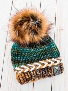 a knitted hat with a pom - pom sitting on top of it