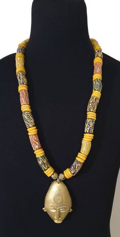 Make a statement in our bold Ghanaian bead necklace with an African mask pendant.  Beads are made from recycled glass and are also known as the Krobo Bead. Unique Wooden Beads Necklace For Festivals, Unique Wooden Beaded Necklaces For Festivals, Unique Beaded Necklaces With Wooden Beads For Festivals, Artisan Yellow Beaded Chain Necklace, Artisan Yellow Necklaces For Festivals, Traditional Yellow Necklaces With Wooden Beads, Artisan Yellow Necklaces With Wooden Beads, Artisan Yellow Necklace With Wooden Beads, Yellow Artisan Necklace With Large Beads