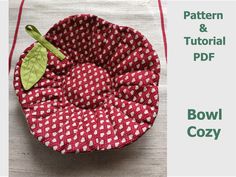 a red and white bowl sitting on top of a table next to a green leaf