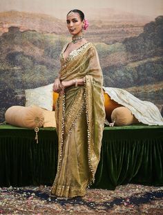 This chic tissue sari is an exquisite embodiment of timeless elegance, featuring delicate dabka work and a gotta patti border adorned with ghumroos. Paired with a chanderi silk blouse embellished with intricate mirror work, this ensemble blends traditional craftsmanship with a modern flair, perfect for elevating your festive look. Dola Silk Chandbali Pre-draped Saree For Diwali, Gold Chanderi Pre-draped Saree With Gota Work, Semi-stitched Saree With Sheer Dupatta For Festive Occasions, Gold Pre-draped Saree With Sheer Dupatta For Navratri, Festive Pista Green Chanderi Pre-draped Saree, Festive Pre-draped Saree With Gota Work, Festival Chanderi Pre-draped Saree With Gota Work, Pista Green Pre-draped Saree With Zari Work For Diwali, Festive Anarkali Pre-draped Saree In Chinon