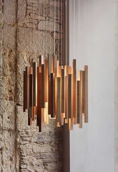 a wooden chandelier hanging from the side of a stone wall