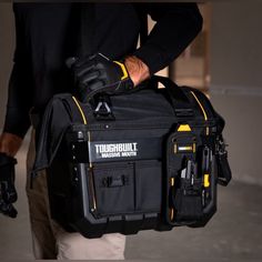 a man carrying a black tool bag with tools in it's pocket and gloves on his hands