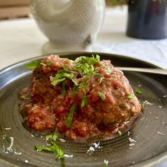 meatballs covered in marinara sauce and parsley on top of a silver plate