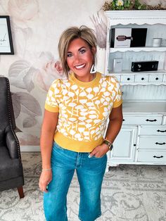 This short-sleeve knit top is about to become your new go-to for effortless style. In a rich mustard hue, it's a vibrant pop of color that brightens up your wardrobe. A button keyhole in back adds a flirty, feminine touch to this lightweight sweater. Made from a cozy blend, it's the perfect transitional piece for fall weather. Pair it with distressed jeans and booties for a casual coffee date or style it with a midi skirt and heels for a night out. However you wear it, this versatile staple is s Short Sleeve Knit Top For Day Out, Mustard Short Sleeve Tops For Fall, Yellow Stretch Short Sleeve Top, Short Sleeve Knit Top For Fall Day Out, Fitted Mustard Top For Work, Fall Short Sleeve Knit Top For Day Out, Mustard Fitted Tops For Work, Fitted Short Sleeve Knit Top For Day Out, Fitted Knit Top With Short Sleeves For Day Out