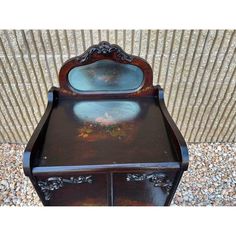 an old fashioned wooden desk with mirror on it's top and bottom drawer, in front of a wall