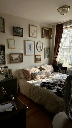 a bed sitting in a bedroom next to a window with pictures on the wall above it