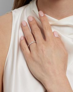 a woman wearing a white dress with a diamond ring on her finger