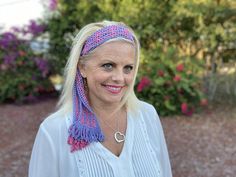 a woman with blonde hair wearing a pink and purple scarf around her neck smiling at the camera