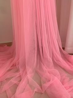 pink sheer fabric draped over a bed in a room with white walls and flooring