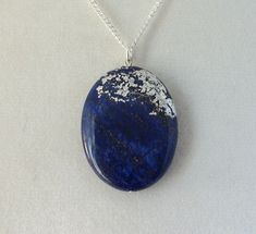 This pendant features delicate silver leaf work on a natural stone. The metal is treated with a micro-crystalline wax to preserve and protect the silver work. The chain measures 18 inches. The pendant is approximately 30 x 40 mm. Silver Lapis Lazuli Round Pendant Jewelry, Silver Necklace With Large Oval Pendant, Silver Lapis Lazuli Round Pendant Necklace, Silver Necklace With Round Lapis Lazuli Pendant, Silver Lapis Lazuli Gemstone Necklace, Oval Pendant Lapis Lazuli Jewelry Gift, Nickel-free Silver Lapis Lazuli Necklace, Silver Lapis Lazuli Necklaces, Oval Lapis Lazuli Silver Jewelry