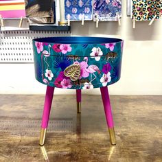 a blue and pink flower pot sitting on top of a wooden table next to pictures