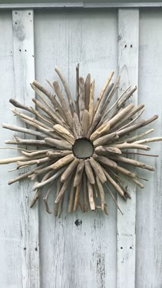 a wreath made out of driftwood is hanging on a white wooden door with wood slats