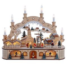 a christmas village with lit candles and people in the snow, surrounded by trees and buildings