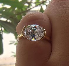 a close up of a person's hand holding a ring with a diamond in it