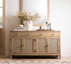 a wooden cabinet with wicker doors and drawers in front of a large mirror on the wall