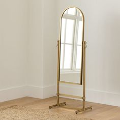 a large gold mirror sitting on top of a wooden floor next to a white wall