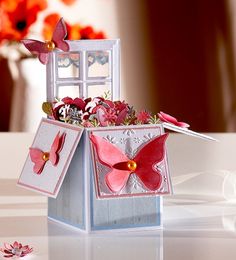 a small box with some flowers in it and a butterfly on the top of it