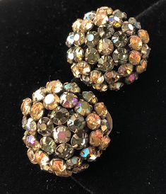 "Here is a lovely pair of vintage earrings by designer Schreiner of New York. The jewelry is beautifully designed with glittering faceted rhinestones in an enchanting color combination of topaz, green and aurora borealis hues. The setting is in gold tone metal and the earrings are in a clip on style. The earrings measure 1\" across. This jewelry is signed with the designer's hallmark on the back of one of the earrings. Noted is a slight difference between the round shape of each earring as well Evening Multi-stone Round Earrings, Sparkling Round Evening Earrings, Dazzling Formal Clip-on Earrings With Sparkling Stones, Sparkling Round Earrings For Evening, Glamorous Evening Jeweled Clip-on Earrings, Glamorous Jeweled Clip-on Earrings For Evening, Evening Rhinestone Round Earrings, Rhinestone Round Earrings For Evening, Evening Earrings With Bling