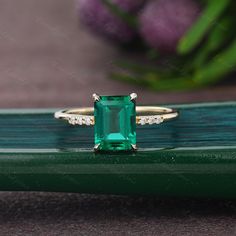 an emerald colored ring sitting on top of a green table