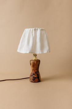 a wooden table lamp with a white shade on it's base and a brown cord