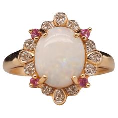 an opalite and diamond ring with pink sapphires on the sides, set in yellow gold