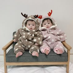 two babies sitting on a chair wearing reindeer costumes