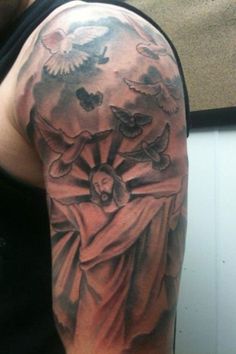 a man with a tattoo on his arm that has an image of jesus and doves