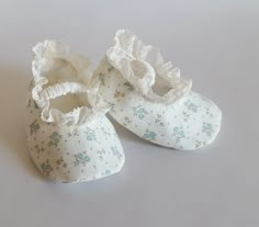 two white baby shoes with blue flowers on them