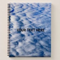 a spiral notebook with clouds and the text your text here