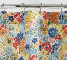 a floral shower curtain hanging on a metal rod