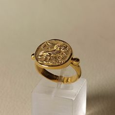 Ring  with the figure of an owl made of 14 carat solid  yellow gold which is the one side of the Athenian coin Tetradrachm ( four drachmas ) Owl was the secret bird  of Goddess Athena and the symbol of wisdom in ancient  Greece The olive tree branch on the coin is the symbol of piece and victory, A beautiful gold handmade  ring made in Greece in our workshop in Athens A wonderful value gift for your self or for those you love The ring can be made also in 18K or 9K  in rose gold or in white gold For more information don't hesitate to contact us SHIPPING INFORMATION FREE SHIPPING VIA DHL EXPRESS Please fill in an active phone number  It's required by the courier company DELIVERY TIME INFORMATION 1 - 3 Days EUROPE 3 - 5 Days to U.S.A and CANADA 5 - 8 Days to AUSTRALIA, SOUTH AMERICA, AFRIKA A Ancient Style Yellow Gold Signet Ring Gift, Mythological Style Gold Coin Pendant Jewelry, Gold Coin-shaped Signet Ring For Gift, Owl Ring Gold, Owl Gold Necklace, Handmade Gold Ring, Lapis Jewelry, Athena Goddess, Elegant Bracelet