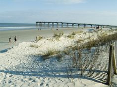 the beach is covered in snow and sand as people walk on the water's edge