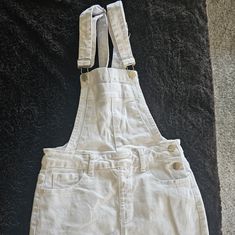 White Denim Overall Skirt. It Is A Short Skirt With Two Adjustable Straps And A Relaxed Fit. The Skirt Has Five Pockets, Two In The Front, Two In The Back, And One On The Chest. The Skirt Is A White Color And Is Made Of A Thick, Sturdy Denim Material. Never Worn. Size S Runs Small. Skirt Waist 13 1/2 Inch Skirt Length 15 1/2 Overalls Skirt, Skirt Overalls, Small Skirt, Overall Skirt, Skirt Short, Denim Material, Short Skirt, White Denim, Skirt Length