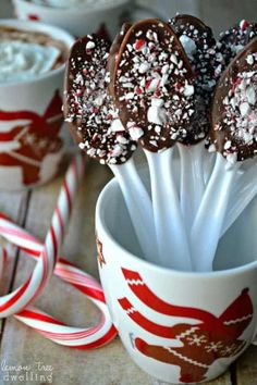 chocolate covered candy lollipops are in a cup with white and red sprinkles