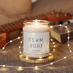 it's wine o'clock candle sitting on top of a table next to a guitar