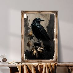 a black bird sitting on top of a wooden table next to a painting hanging on the wall