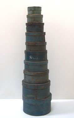 a tall stack of metal containers sitting on top of a white table next to a wall