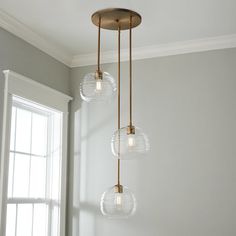 three clear glass globes hang from a brass chandelier in an empty room