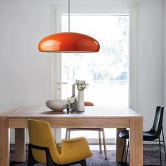 a dining room table with two chairs and an orange light hanging from the ceiling over it