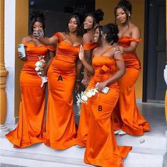 a group of women in orange dresses standing on steps