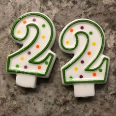 two white and green birthday candles with dots on them sitting on a marble counter top