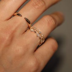 a woman's hand with a gold ring and diamond band on her left wrist