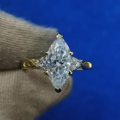 a woman's hand holding a ring with a pear shaped diamond in the center