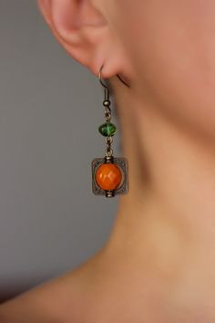 Beautiful and unique boho earrings with orange czech glass faceted 10 mm, green irregular shape glass beads, antique brass  square charms and antique brass earring hooks. Earring hooks are from nickel free and lead free metal. Unique jewelry for your boho outfit or a great gift for someone special! *The total lenght of earrings is about 49 mm including earring hooks. Other earrings of my shop you can see here: https://www.etsy.com/shop/NaTavelli?section_id=13757927  Thanks for visit. Bohemian Orange Copper Earrings, Orange Copper Bohemian Earrings, Bohemian Orange Jewelry Nickel Free, Bohemian Orange Nickel-free Jewelry, Bohemian Orange Czech Glass Earrings, Orange Bohemian Drop Earrings Jewelry, Handmade Orange Copper Earrings, Orange Bohemian Drop Earrings, Bohemian Orange Metal Jewelry