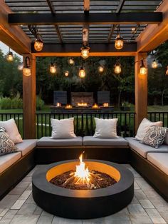 an outdoor fire pit surrounded by couches and lights